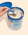 Woman's hand scooping Nara's Organic Infant Formula from the container